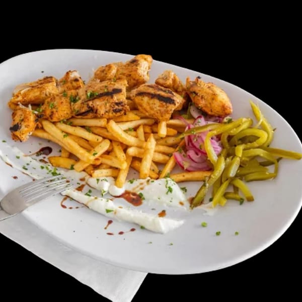 Mediterranean chicken shawarma plate with fries, pickled vegetables, and a fork on a white plate.